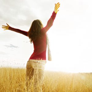 A woman standing in a field with her arms in the air