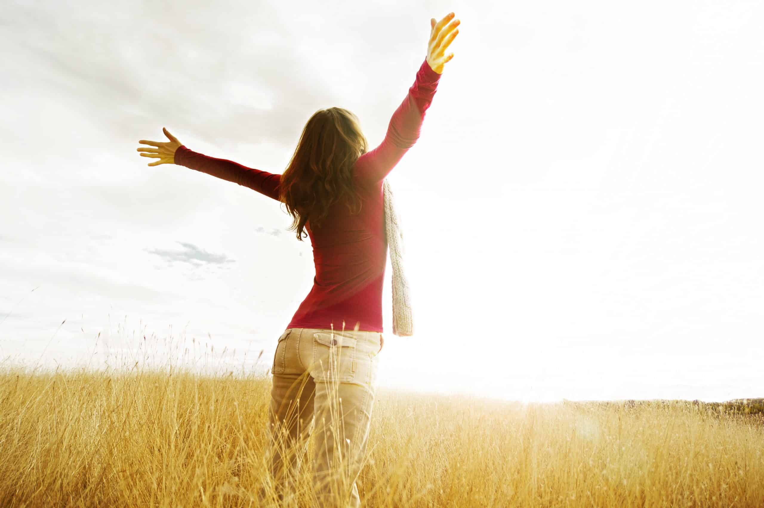 A woman standing in a field with her arms in the air