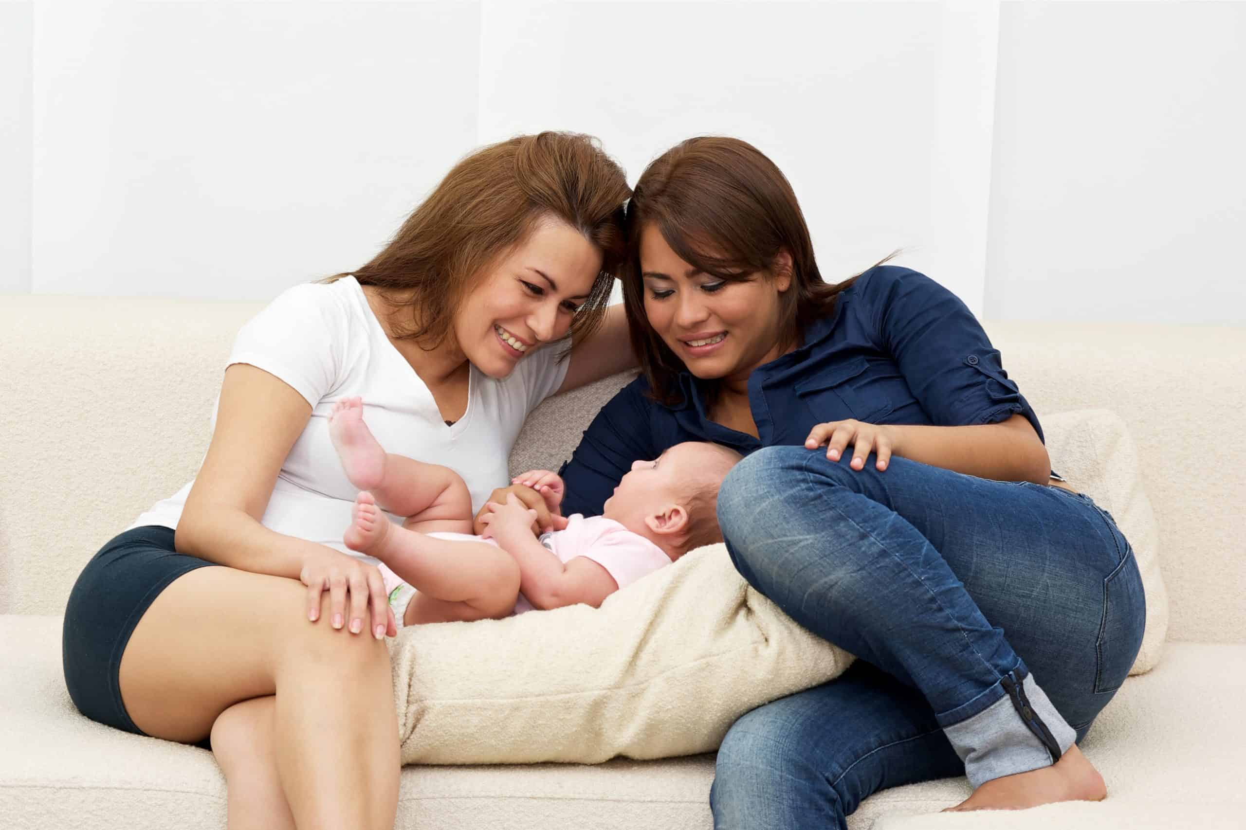 Two women on a couch with their baby.